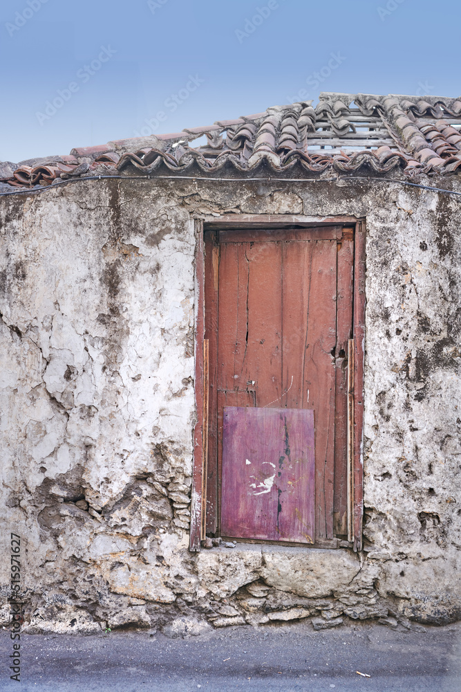 古老的废弃房屋或住宅，有风化的石墙和红色木门。复古和古老的住宅