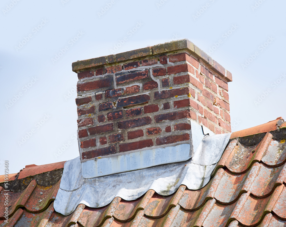 红砖烟囱设计在房屋或建筑物的屋顶上，以天空为背景。建筑