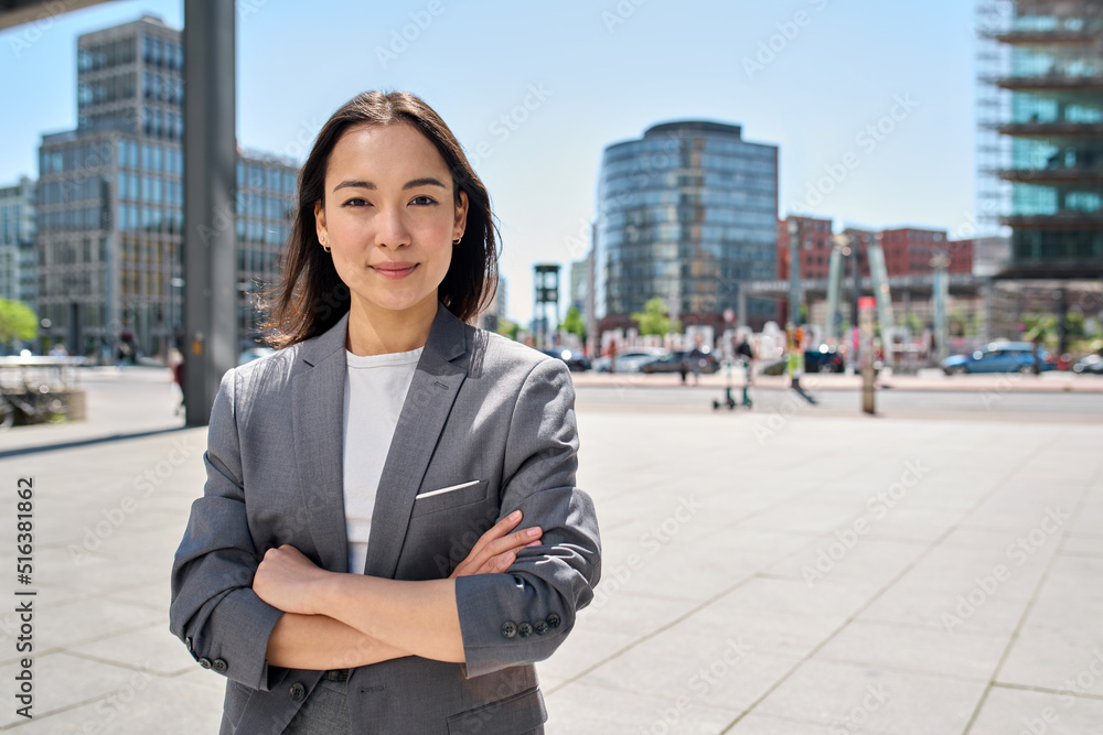 年轻、自信、微笑的亚洲商业女性站在繁忙的街道上，肖像。为成功的fem感到骄傲
