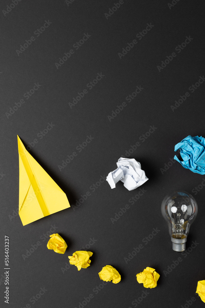 Image of paper balls and plain and light bulb over dark background