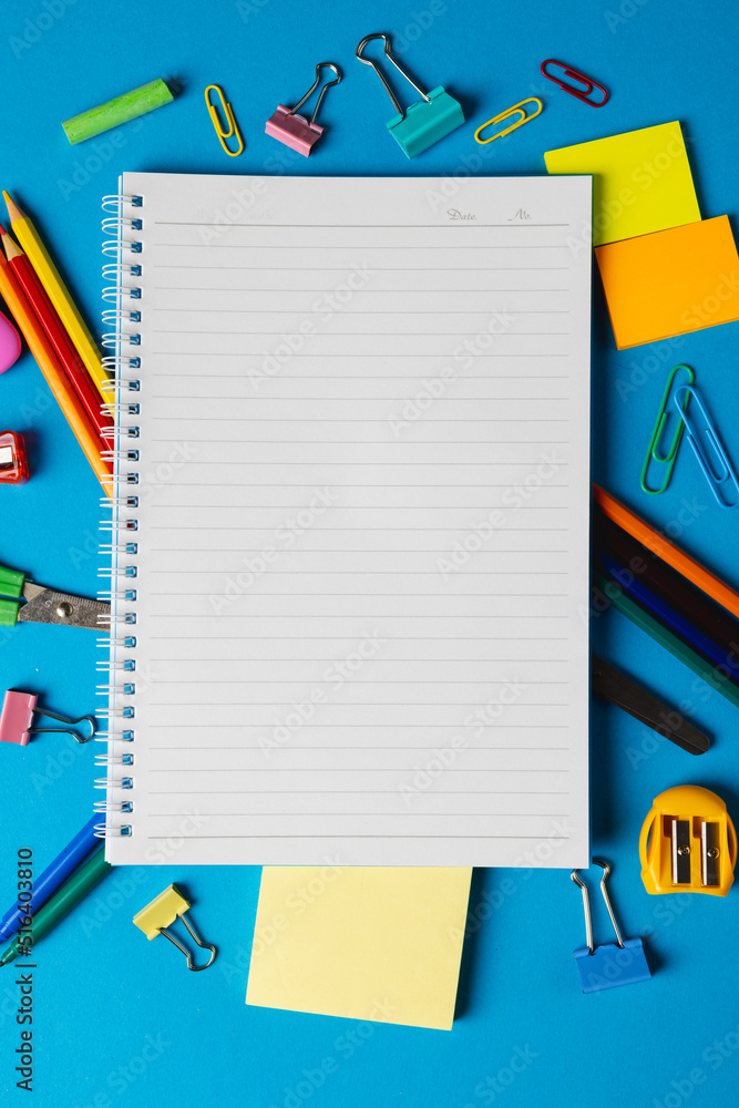 带笔记本的学校设备垂直构图，蓝色表面有复印空间