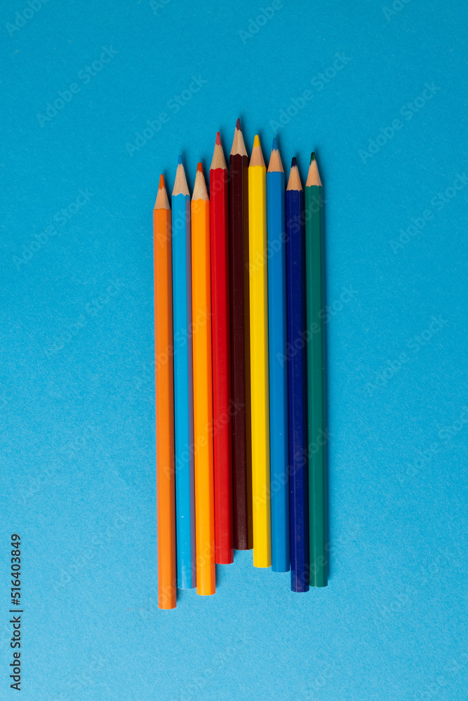 Vertical composition of colorful crayons on blue surface with copy space