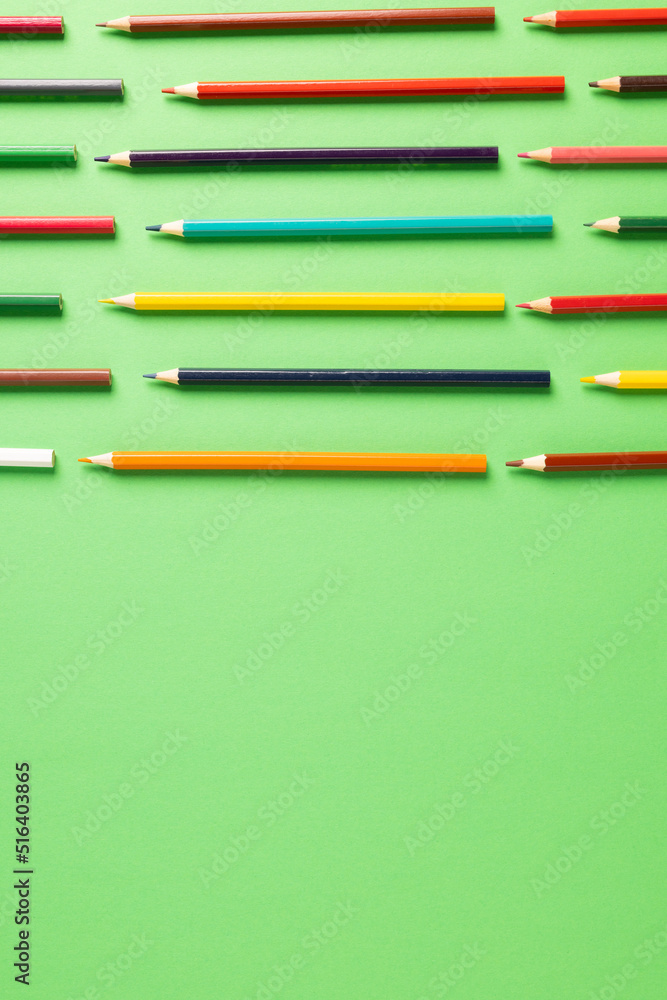 彩色蜡笔在带有复制空间的绿色表面上的垂直构图