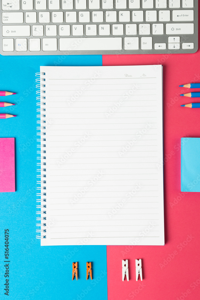 蓝色和粉色表面带有复印空间和学校设备的笔记本的垂直构图