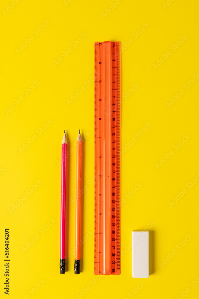 黄色表面上的标尺、铅笔和橡皮擦的垂直构图