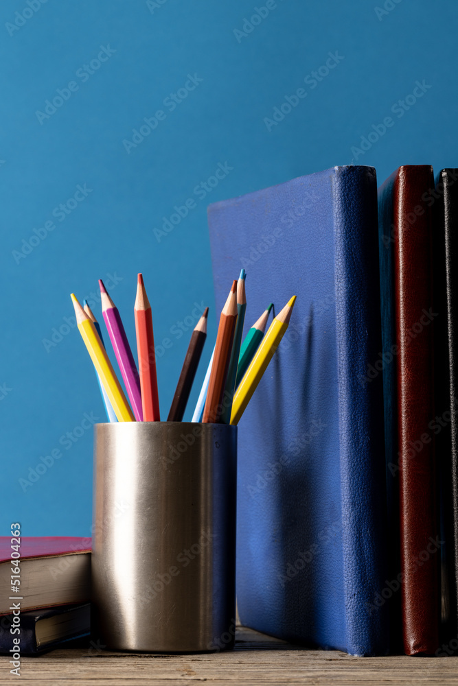 蓝色表面上容器中书籍和蜡笔的垂直图像