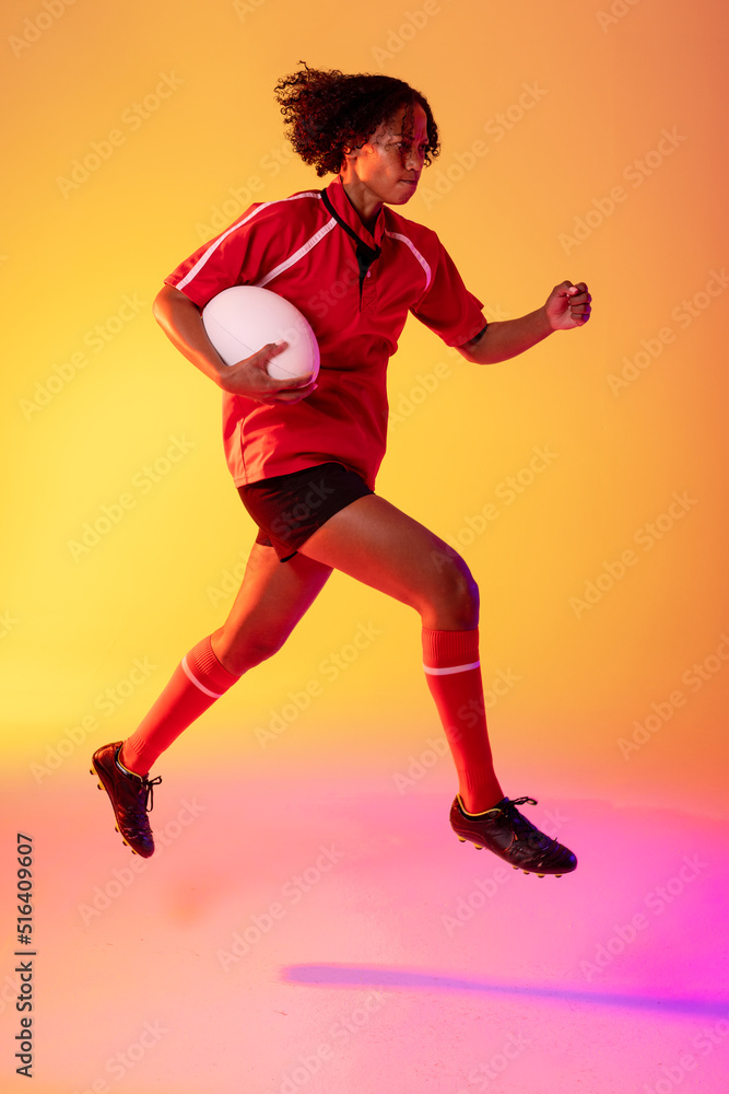非裔美国女橄榄球运动员拿着橄榄球在霓虹灯下奔跑