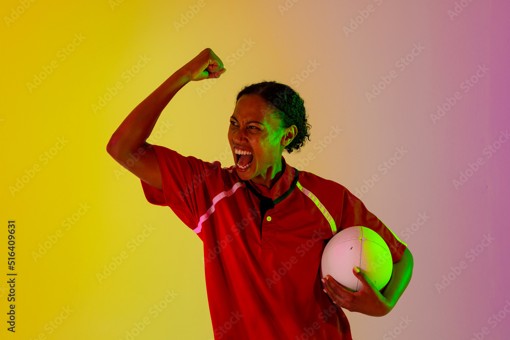 非裔美国女橄榄球运动员在霓虹灯下举起橄榄球