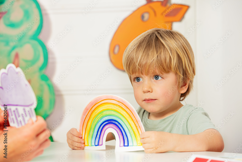 幼儿园班男孩拿着彩虹牌推车