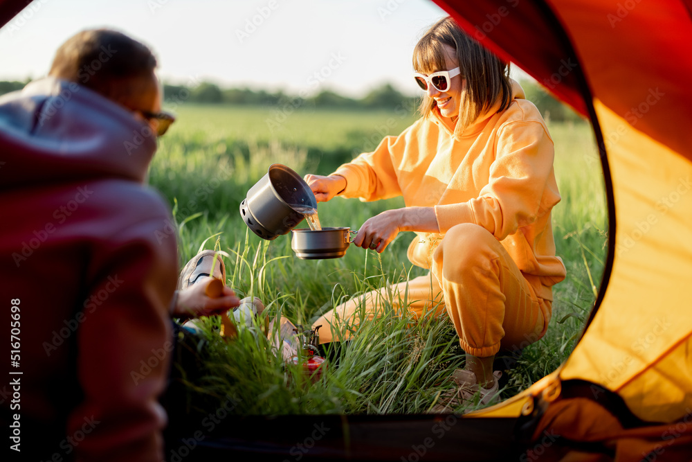 一对年轻夫妇带着帐篷在大自然中旅行时准备食物。一男一女在ca度过夏天