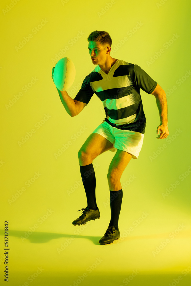高加索男子橄榄球运动员在黄色灯光下拿着橄榄球