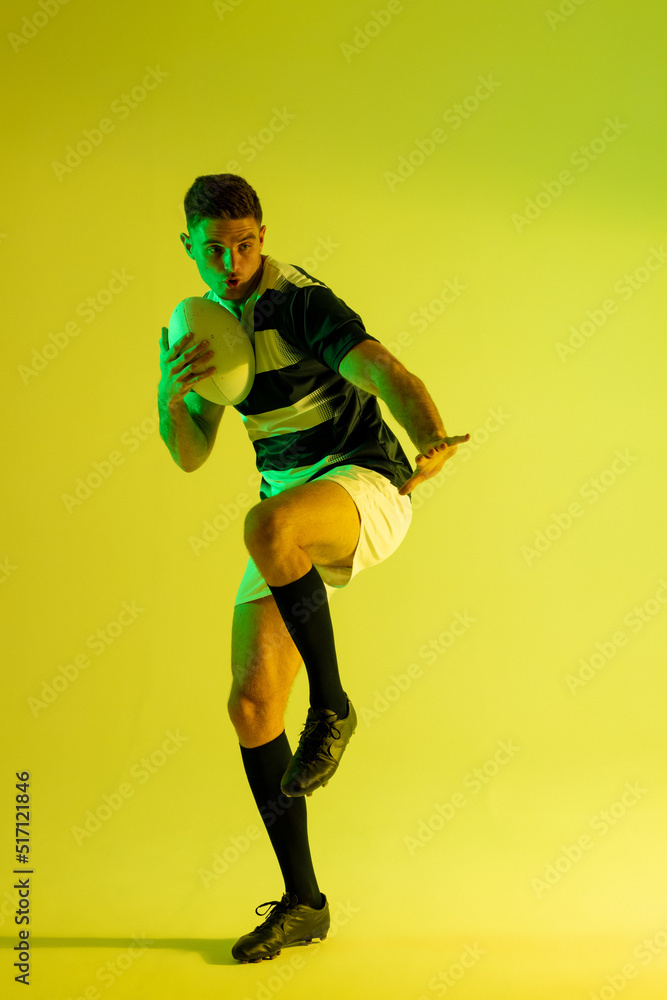 高加索男子橄榄球运动员，黄色灯光下拿着橄榄球