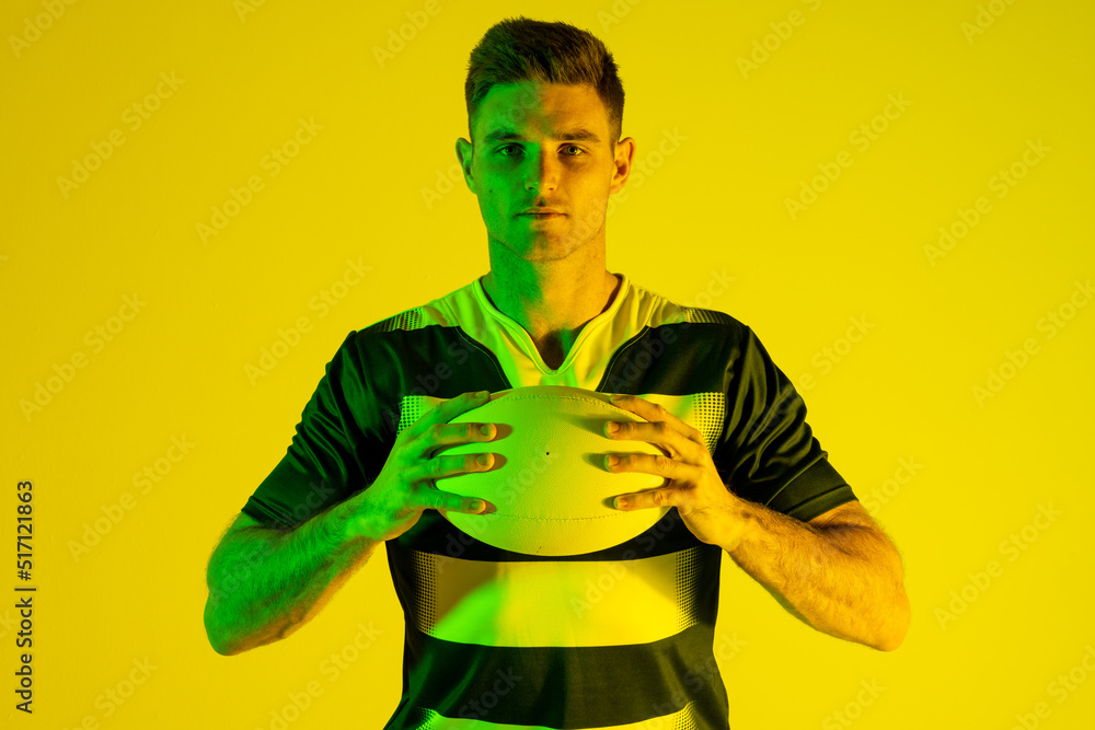 高加索男子橄榄球运动员的肖像，黄色灯光下有橄榄球