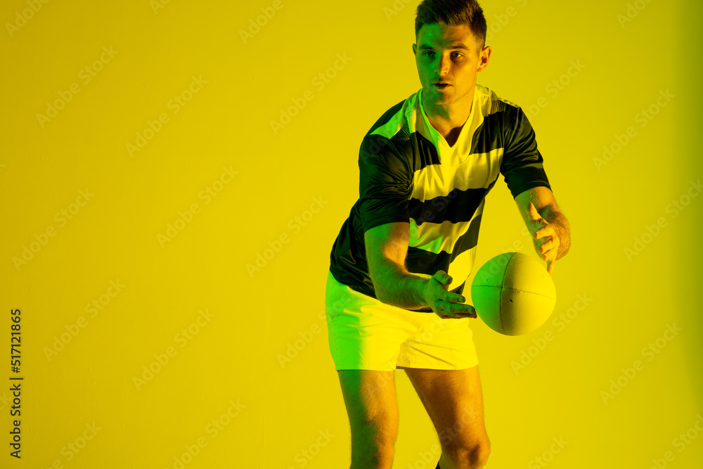 高加索男子橄榄球运动员在黄色灯光下接球