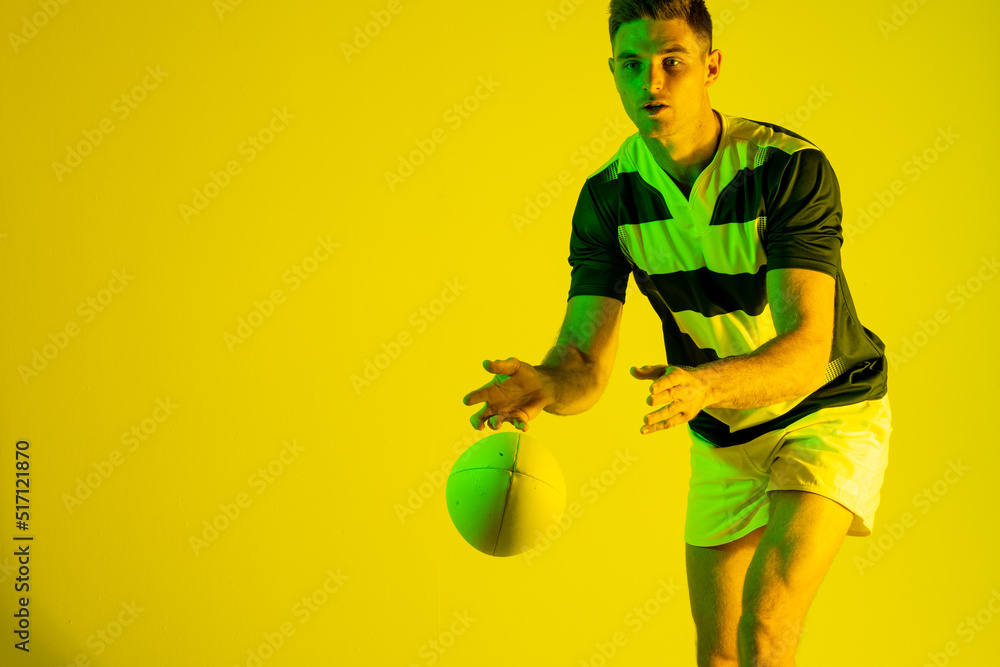 高加索男子橄榄球运动员在黄色灯光下接球