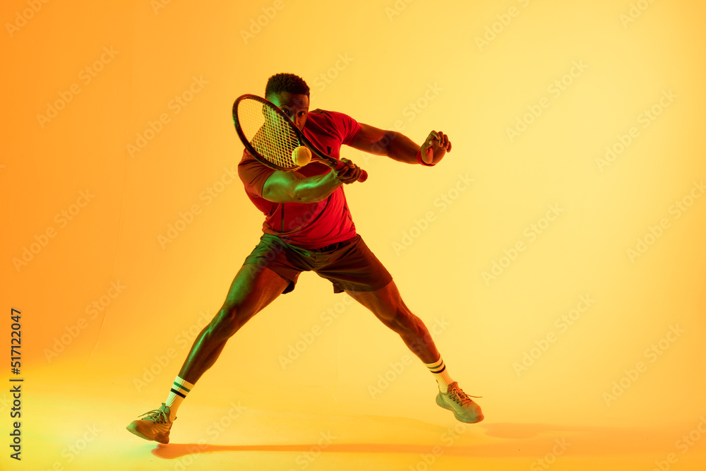 非裔美国男子网球运动员在黄色灯光下击球的画面