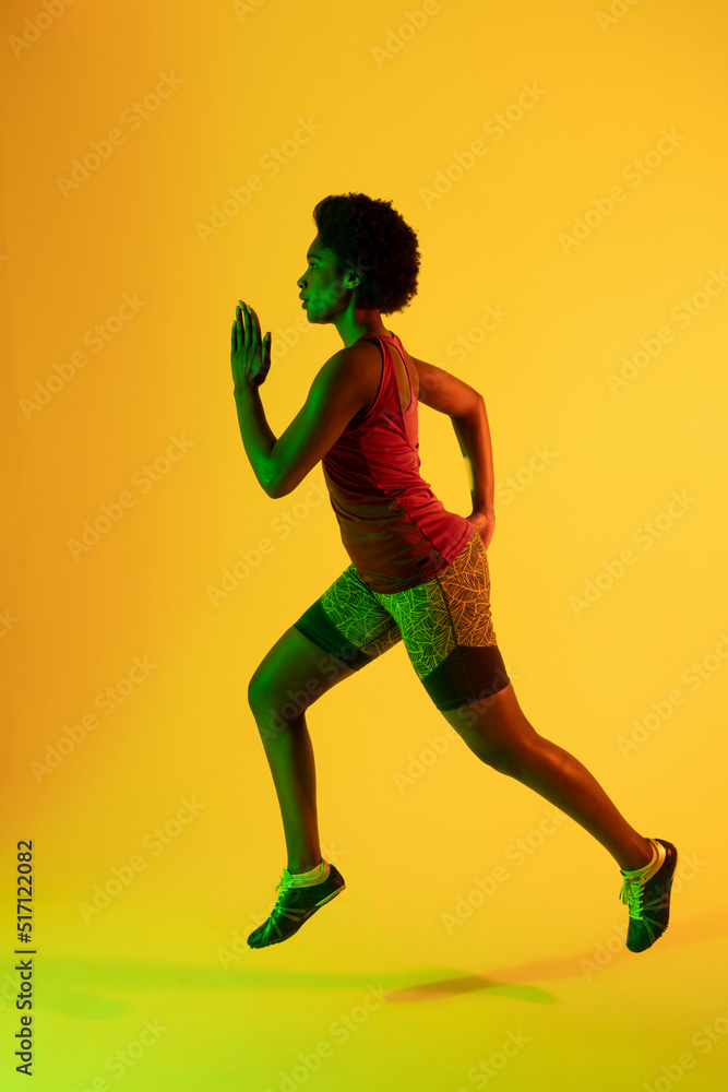 非洲裔美国女运动员在黄色灯光下奔跑的垂直图像