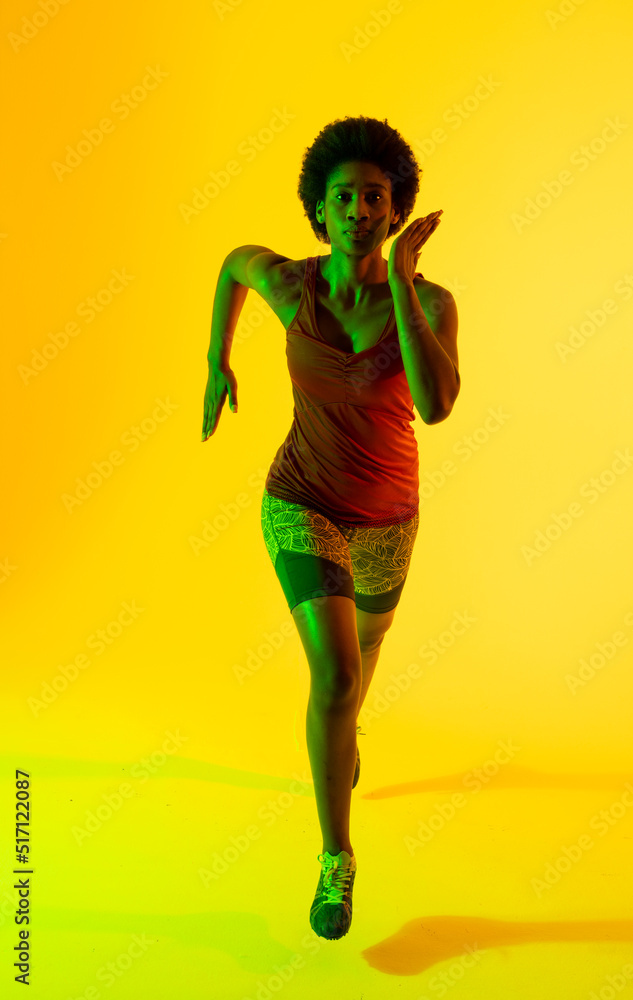 非洲裔美国女运动员在黄色灯光下奔跑的垂直图像