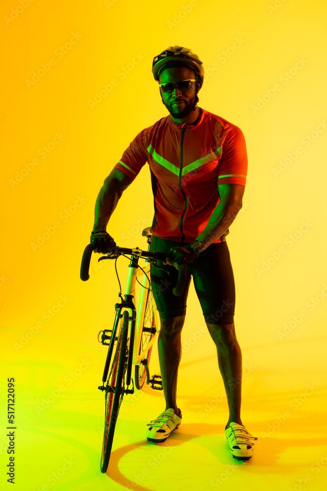 非裔美国男自行车手在黄色灯光下看着摄像机的垂直图像