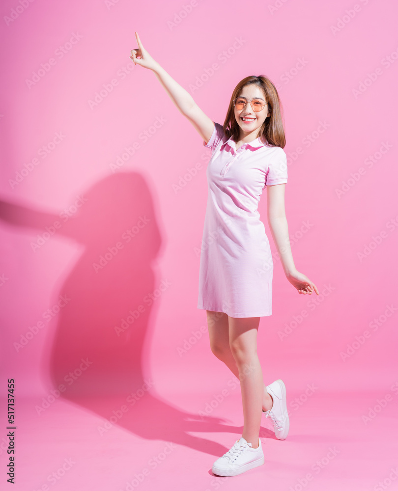 Full length photo of young Asian girl on pink background