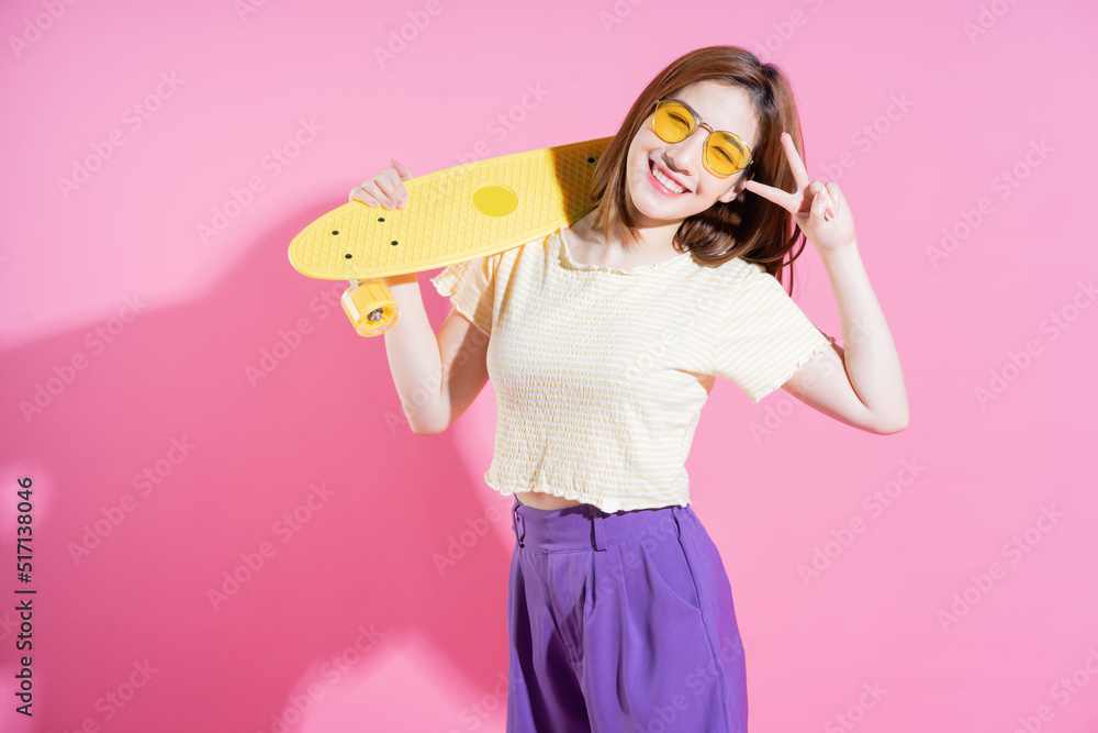 Photo of Asian teenager girl with skateboard on pink background