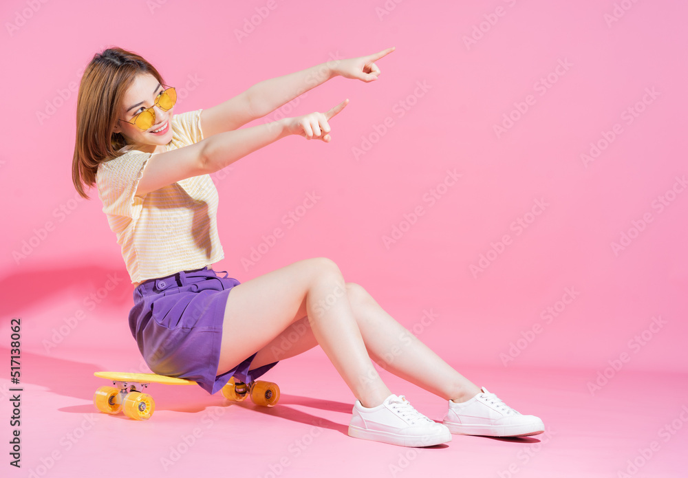 亚洲少女粉色背景滑板照片