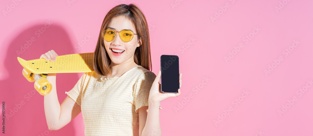 亚洲少女粉色背景滑板照片