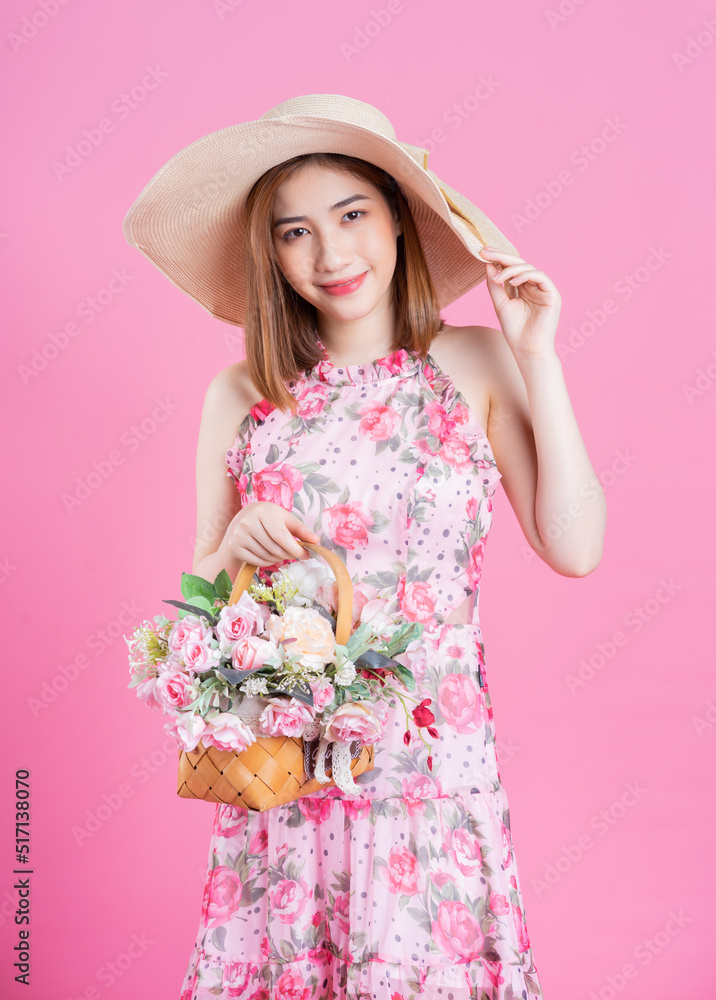 年轻的亚洲女孩穿着粉色背景的花朵连衣裙的照片