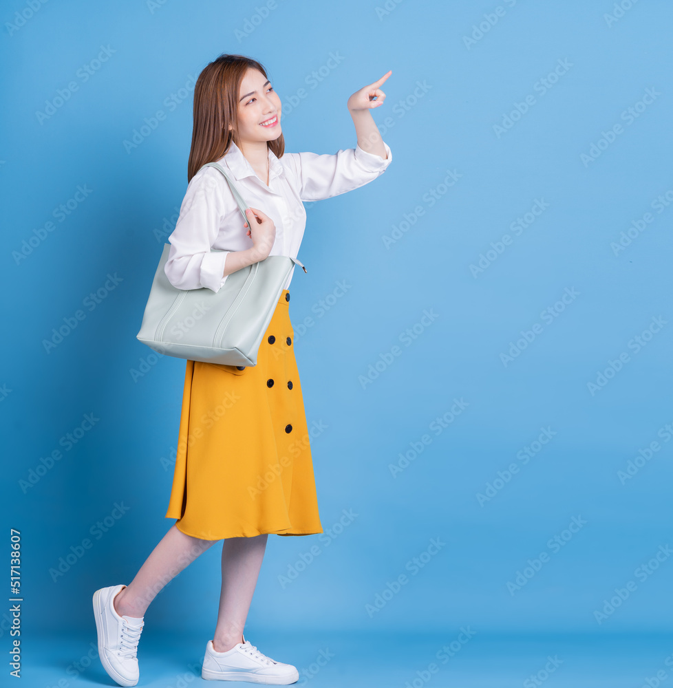 Full length photo of young Asian woman on blue background