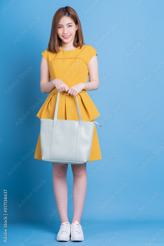 Full length photo of young Asian businesswoman on blue background