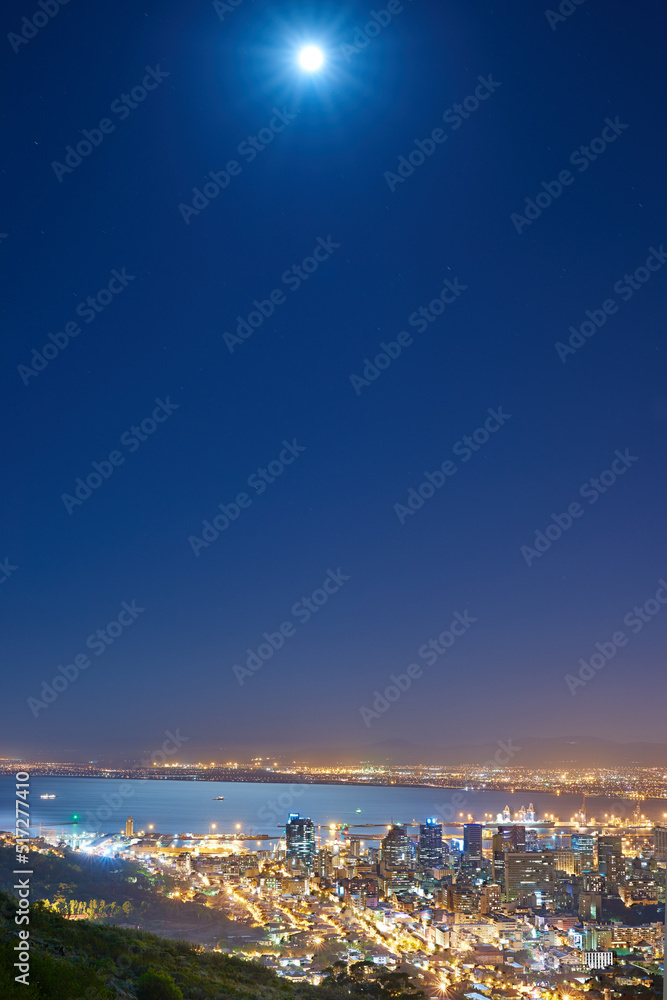 Urban city lights with a full moon in the midnight sky with copy space. Skyline with colorful lighti