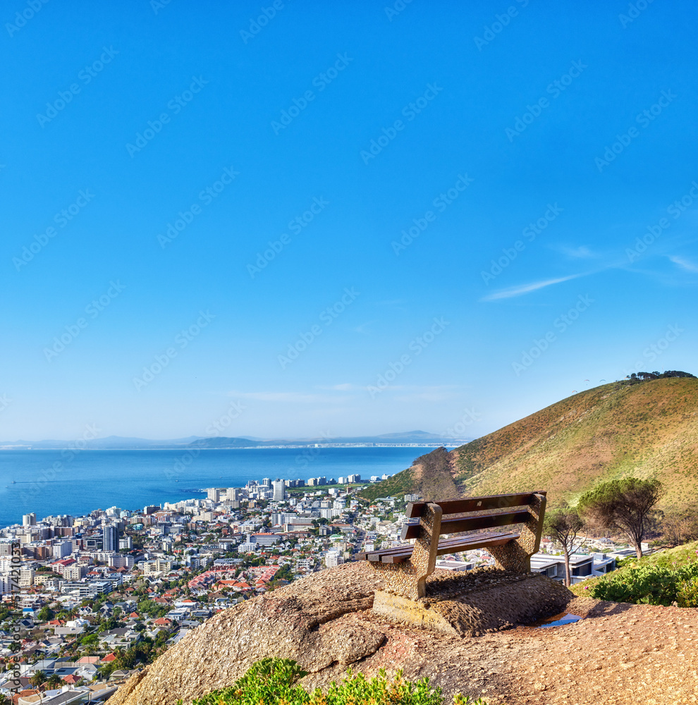 Beautiful aerial view of empty bench overlooking city and ocean in Cape Town, South Africa against b