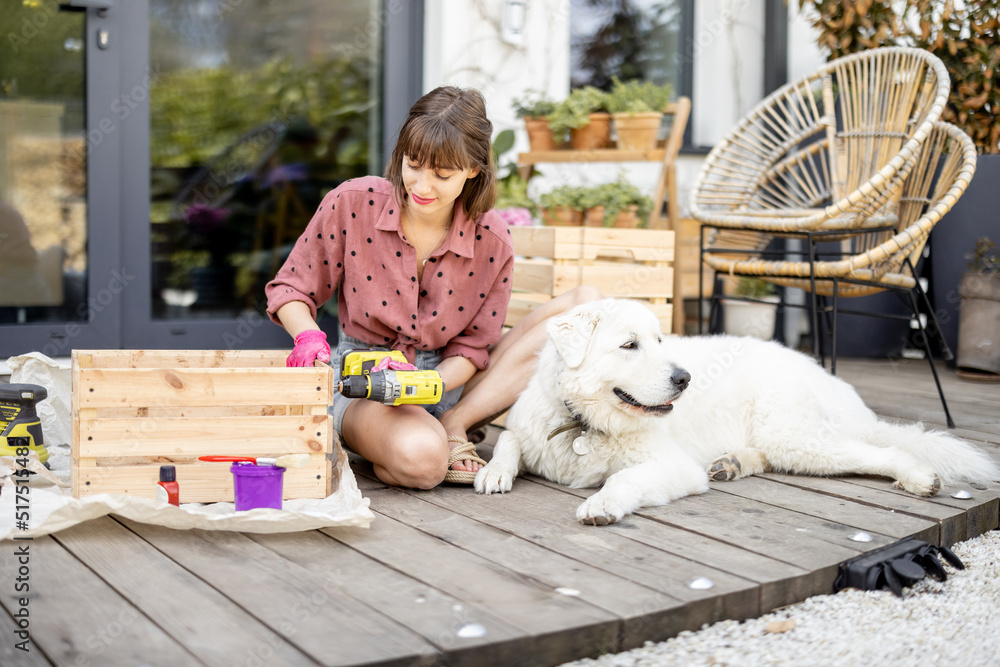 年轻快乐的家庭主妇和她的狗坐在她家的木露台上做木箱