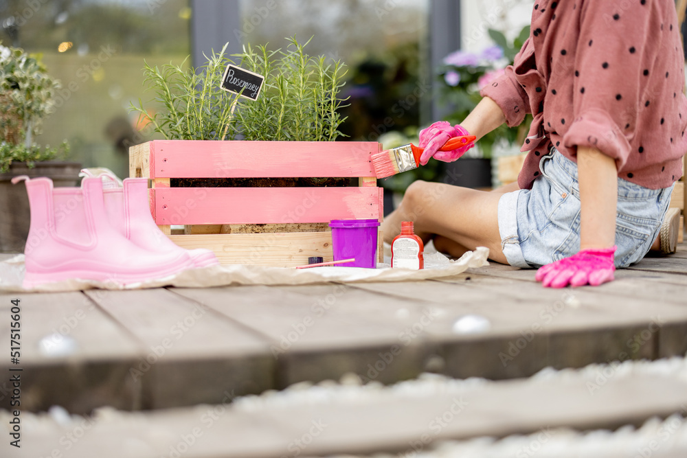 一个手巧的女人用粉色的刷子木箱画画，在户外做一些翻新家务。