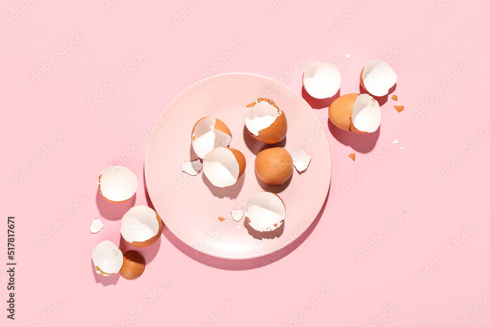 粉红色背景上有碎蛋壳的盘子