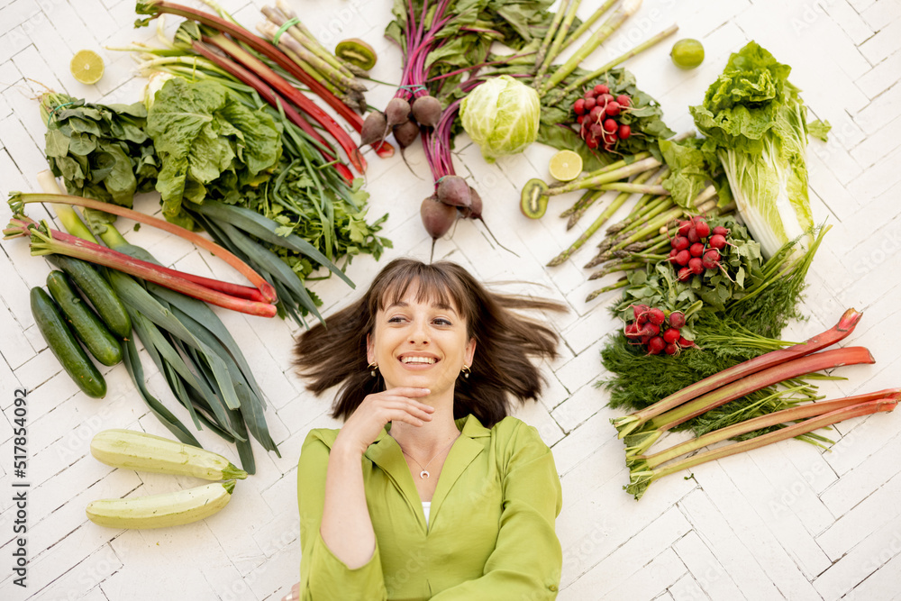 一个年轻快乐的女人的画像，她的头顶上有很多新鲜的蔬菜、水果和绿色蔬菜，