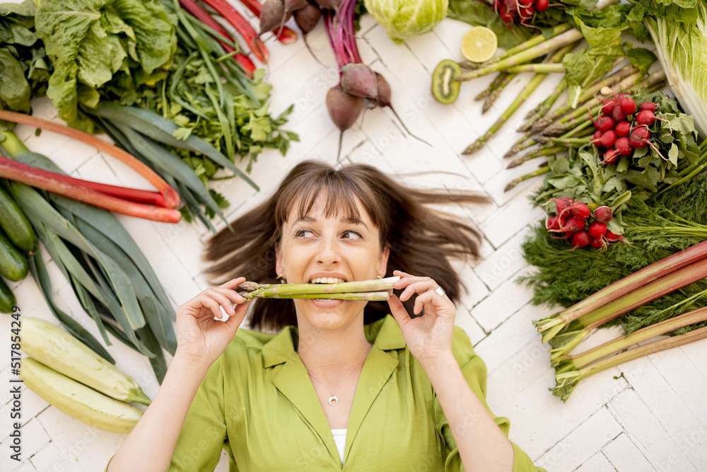 一个年轻快乐的女人的画像，她的头顶上有很多新鲜的蔬菜、水果和绿色蔬菜。
