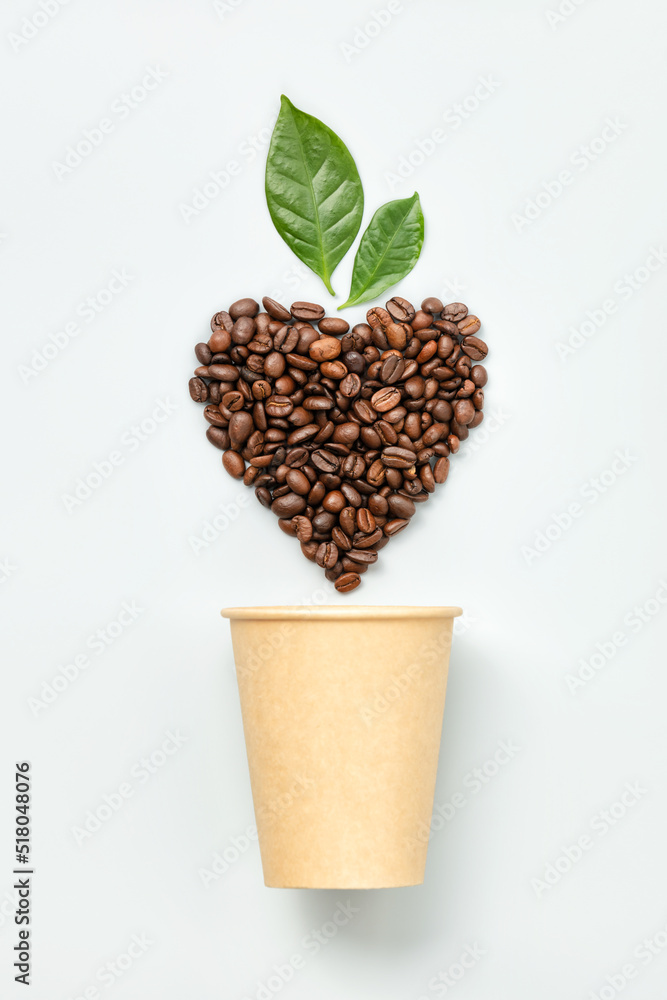 White coffee cup and coffee beans in shape of heart on white background