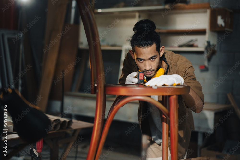 亚洲青年木匠在木工工作台上用卷尺测量椅子