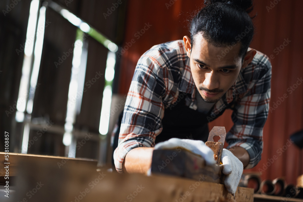 年轻的亚洲男子木匠在木工工作中使用辐条装饰木制品