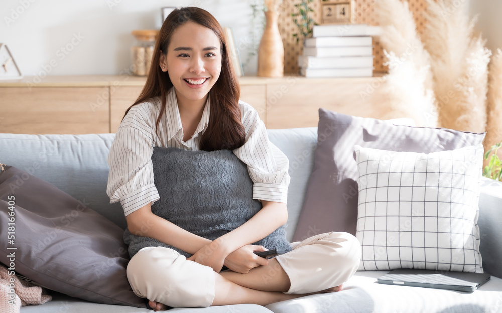 Asian woman happily watch tv comedy series on sofa living room at home