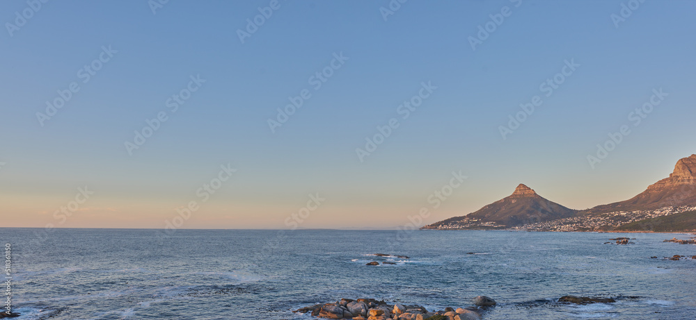 Beautiful view of a calm ocean and mountains with a blue sky background and copy space. Stunning nat