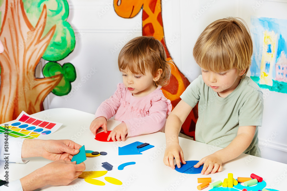 一个男孩和一个女孩在幼儿园的桌子上组合形状