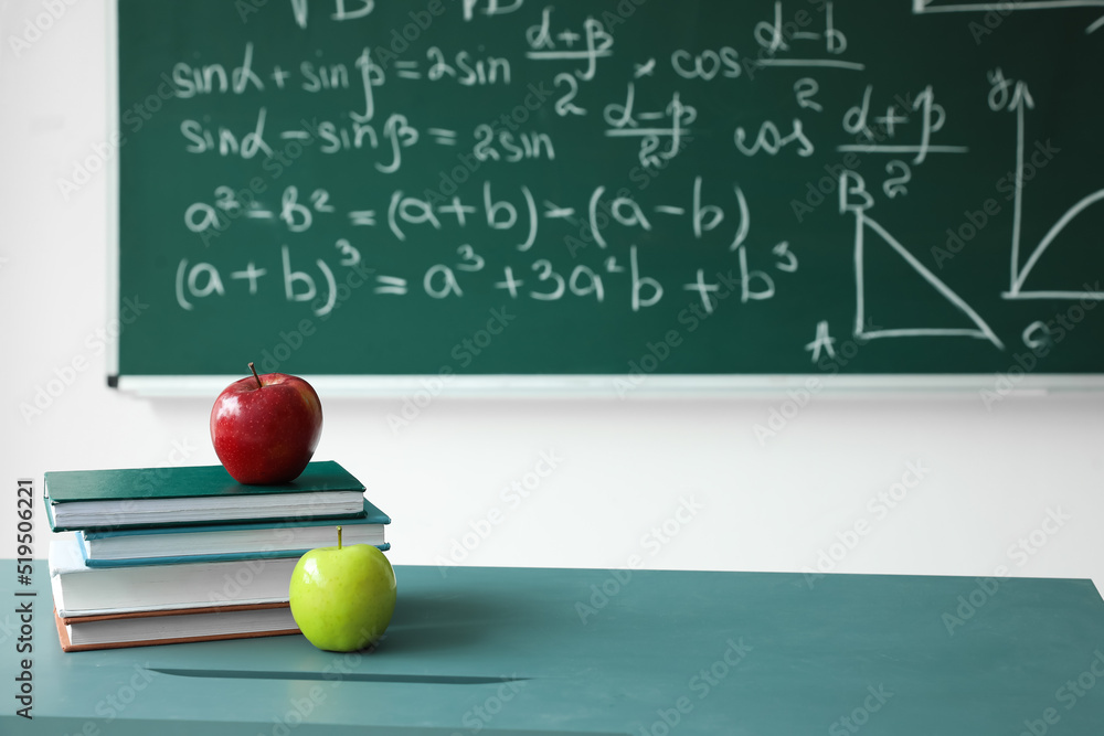 黑板附近桌子上的苹果和课本