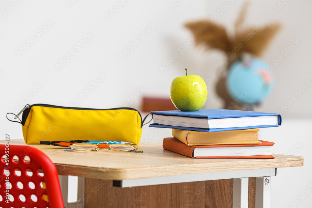 教室桌子上放着课本和铅笔盒的苹果