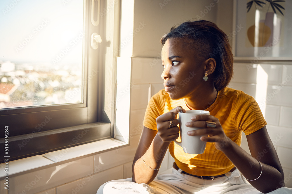 一位思维敏捷、喝着咖啡的黑人女性凝视窗外，享受着早晨的日常生活