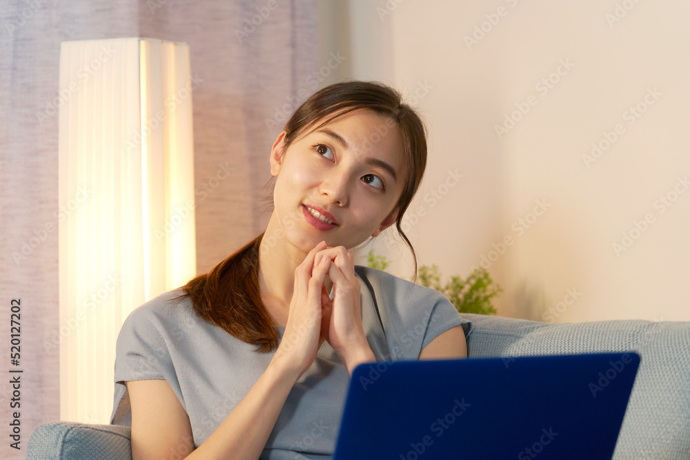 夜にリビングでパソコンを見て想像する女性
