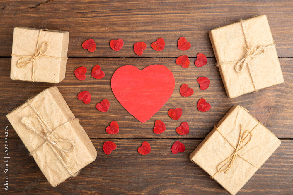 情人节问候概念。木质背景上的小红木心和礼品盒