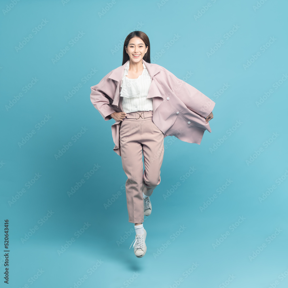 Young beautiful asian woman with smart casual cloth wearing pink coat smiling and jumping isolated o