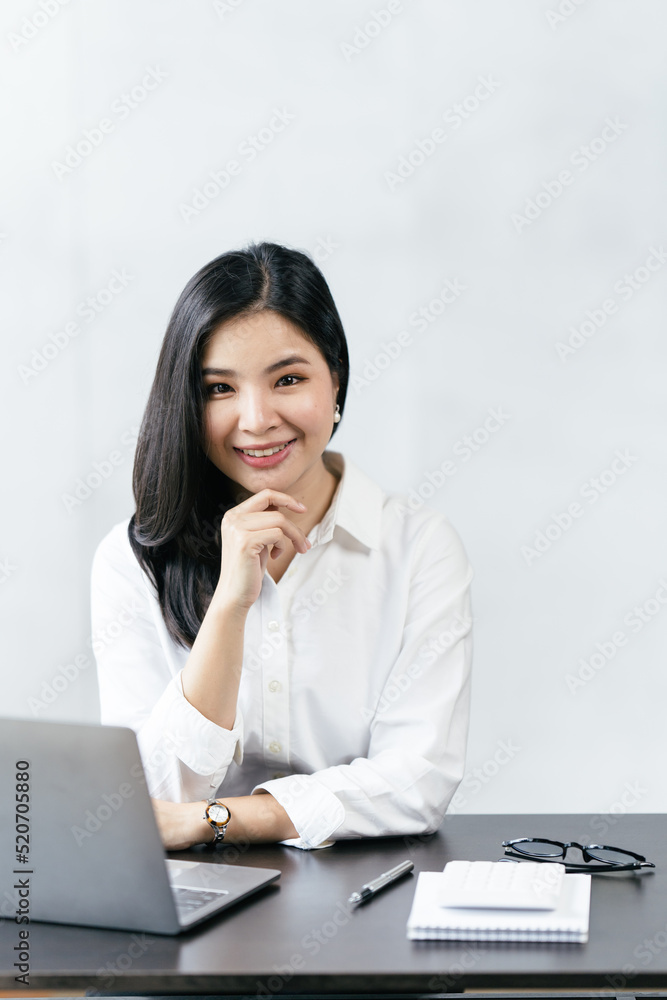 亚洲女商人坐在家里用笔记本电脑，微笑着在家工作。